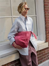 Sideview of Charlize Theron in sunglasses holding a pink purse and wearing oversized clothes