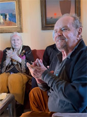 Sideview of Jack Nicholson sitting on a couch. Joni Mitchell is seated in the background