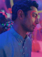 Riz Ahmed in Bait. He has glow in the dark makeup on at a club