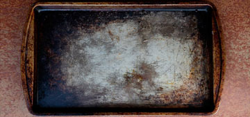 Is it possible to fully clean grease stains from dirty baking sheets?