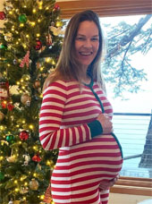 Hilary Swank in front of a Christmas tree wearing striped pajames while pregnant with twins, via Instagram